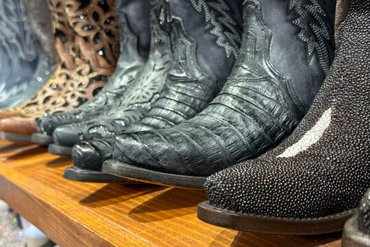 Closeup of row of cowboy boots western clothing retro stylish leather shoes.