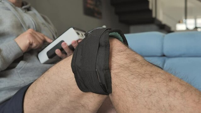 person using magnetotherapy on injured knee at home