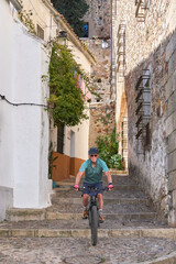 Fototapeta na wymiar active senior man cycling with his electric mountain bike in the medieaval and moorish downtown of Caceres, Extremadura, Spain