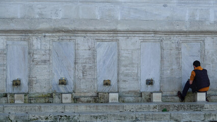 A young man performing ablution in the historical public ablution facility in the courtyard of the...