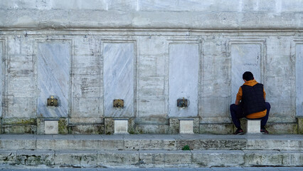 A young man performing ablution in the historical public ablution facility in the courtyard of the...