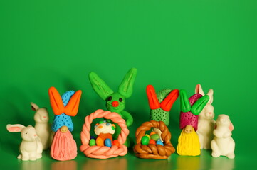 Toy Easter gnomes and rabbits on a green background. Next to the basket with an Easter cake.