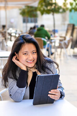 Fototapeta premium Smile happy Asian business woman wearing suit holding digital tablet siting in the street