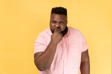This is lie. Portrait of suspicious man wearing pink shirt touching nose, doing liar gesture, body...