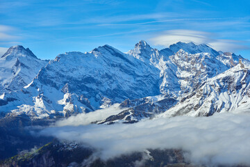 Fototapeta na wymiar Swiss mountain snowy peaks over clouds in the valley. Bernese region in Switzerland.
