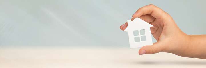 Real estate insurance. Model of a white house in hands on a gray blurred background. Insure a house...