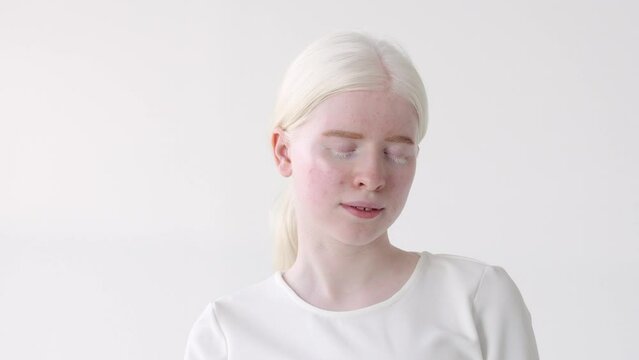Pretty albino teen girl, cute beautiful model wearing white t-shirt standing on white studio background. Inclusive unusual natural beauty, inclusion, albinism and diversity concept.