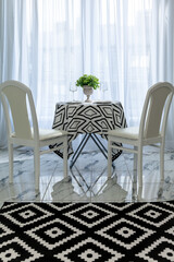 a chic bright living room with a dining table by the window and chairs serving for guests of the apartment