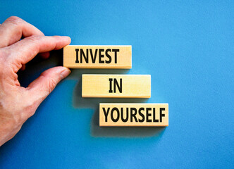 Invest in yourself symbol. Concept words Invest in yourself on wooden block on a beautiful blue table blue background. Businessman hand. Business and Invest in yourself concept. Copy space.