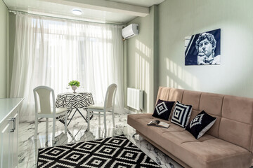wide textile bright sofa with pillows and a blanket in a bright modern living room apartment interior