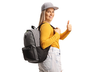 Female student with a backpack looking over shoulder and gesturing thumbs up