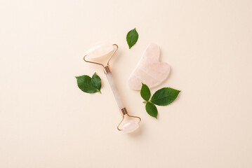 Discover the art of skin care with top view flat lay featuring massage face roller with green leaves on a serene beige background