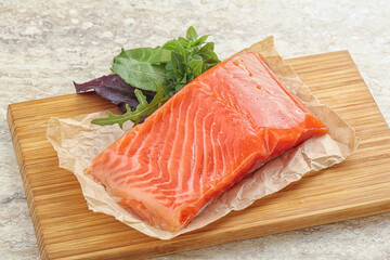 Raw salmon fillet over board