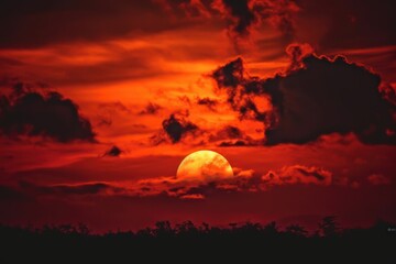 Obraz premium red sun with clouds behind on the dark sky, a red sun with clouds in the background