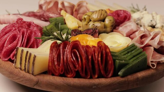 Charcuterie and cheese platter rotates smoothly around its axis. Appetizers boards with assorted cheese, salami, ham, grape and nuts. Video is looped