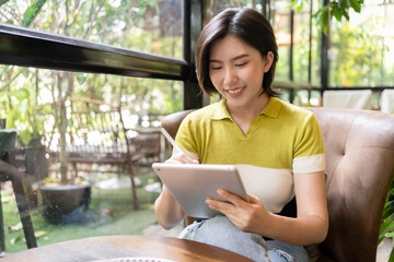 Asian woman using laptop in a cafe full of green plants