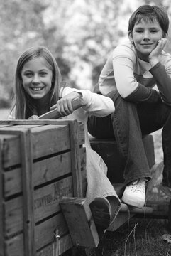 Portrait of Two Girls Sitting On Soapbox Car Outdoors