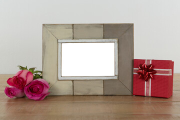 Obraz premium Photo frame, rose flower and gift boxes on a table