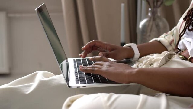 Happy dark skinned  wife doing online shopping via application on digital laptop computer while spending newlywed weekend with carefree husband, smiling couple in love searching web movie on netbook
