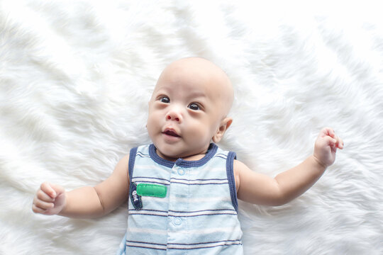 Cute baby boy is shooting in the studio. fashion image of baby and family. Lovely baby lie down on a soft white carpet. image for background, wallpaper, copy space, objects, fashion and article