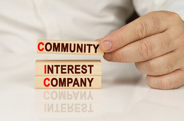 In the hands of a person and on a reflective surface are wooden blocks with the inscription - Community interest company