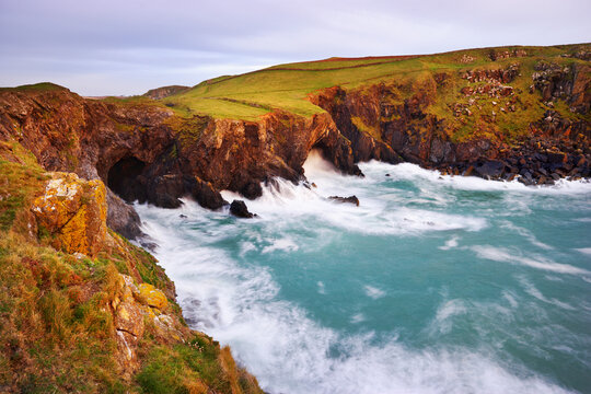 Waves Breaking against Sea Cliffs with Cave, Rumps Point, Cornwall, England