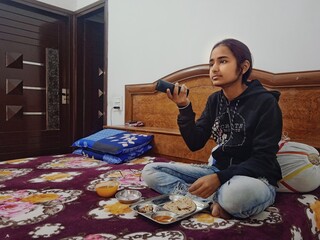 Indian girl warching tv while eating lunch. Reference for spoiled kids or addiction images. 