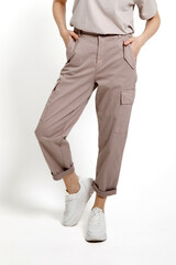 Women's beige pants with white sneakers on a white background.