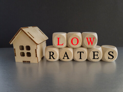Low house rates symbol. Concept words 'Low rates' on wooden blocks near miniature houses. Beautiful black background, gray table, copy space. Business and low house rates concept.