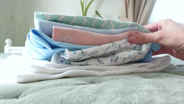 Clean colored clothes on the bed in a bedroom, soft focus background