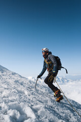 Alpinist climbing a high snowy mountain in Alps.
