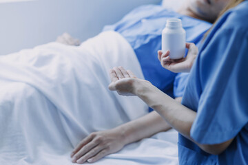 Side view of diverse doctors examining Asian female patient in bed in ward at hospital.