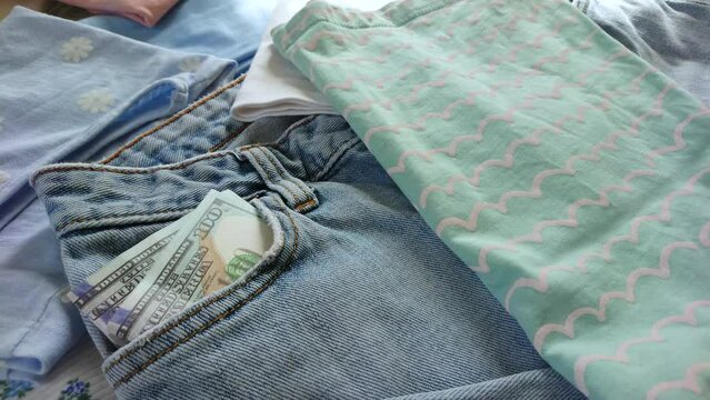 Blue jeans with American dollars in the pocket, top view. Concept of traveling or shopping