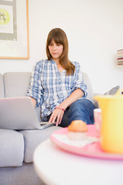 Woman Sitting on Sofa using Laptop Computer