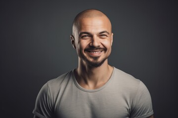 Fototapeta premium Portrait of a bald man in a gray t-shirt on a dark background