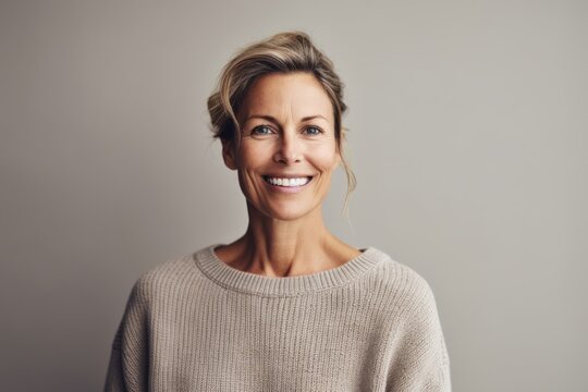 Medium shot portrait photography of a pleased woman in her 40s wearing a cozy sweater against a minimalist or empty room background. Generative AI