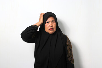 Pensive Middle aged Asian women wearing hijab thinking with hand on head feels confused