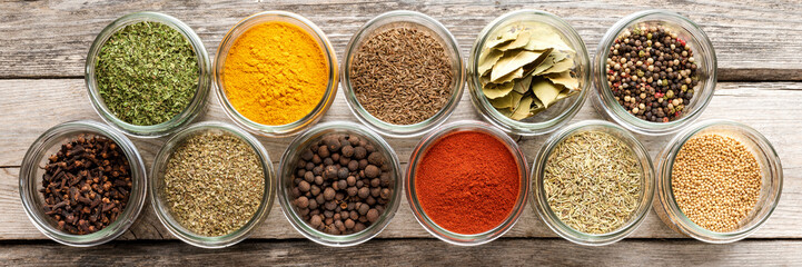 Obraz na płótnie Canvas Mix of colourful spices in bowls on wooden table with copyspace. Collection of seasonings. Top view