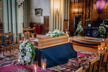 Fototapeta na wymiar A coffin decorated with many flowers and candles in a beautiful church, ceremony