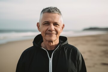 Portrait of smiling senior man standing on beach and looking at camera
