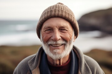 Portrait of smiling senior man in cap and scarf standing at beach