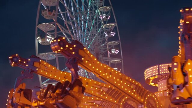 Ferris wheel. People having fun riding roller coaster at the amusement park at night
