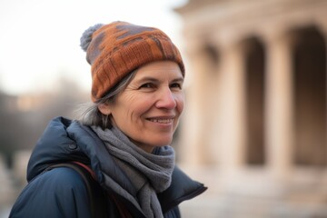 Portrait of a smiling middle-aged woman in a hat and coat in the city