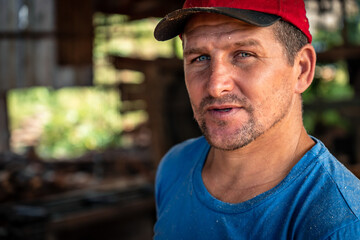 Close up portrait of a handsome male worker wearing a red hat looking at the camera.