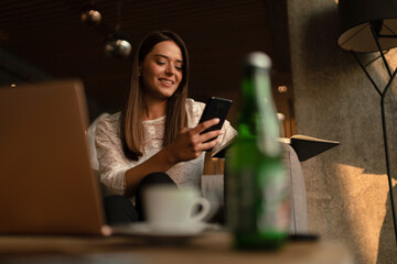 Portrait of a young laughing charming woman looking at her cell phone