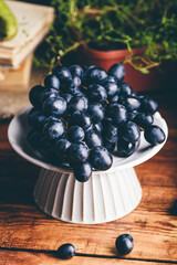 Close Up of Dark Blue Grapes on a White Plate on Wooden Table