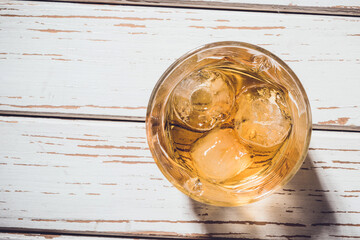 Whiskey glass with ice cubes on an old wooden table