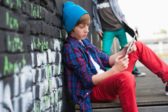 Boy Sitting and using a Tablet PC Outdoors, Mannheim, Baden-Wurttemberg, Germany