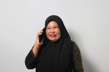 Frowning Middle aged Asian women wearing hijab making a phone call
