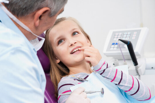 Girl Showing Tooth to Dentist during Appointment, Germany